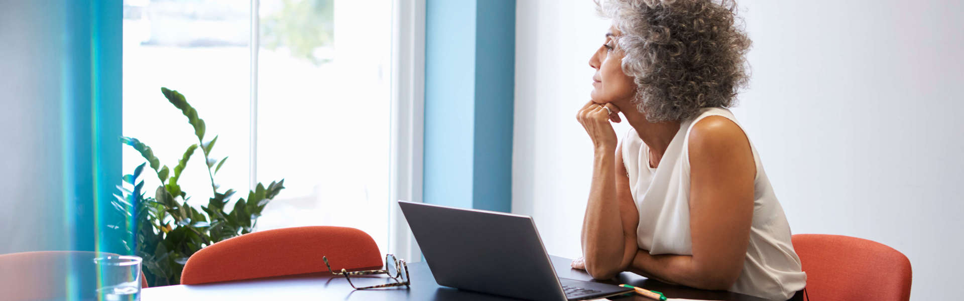 Woman working on laptop at desk staring out of window