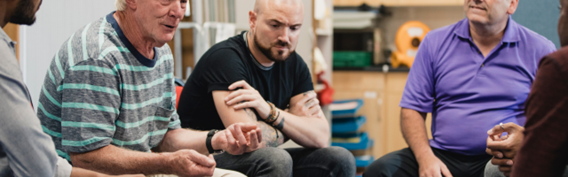 Group of men sat in circle at support group meeting